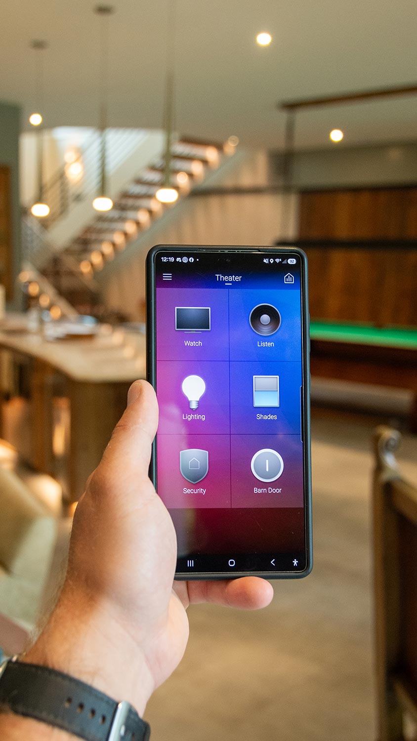 Hand holding a smartphone displaying a smart home control app