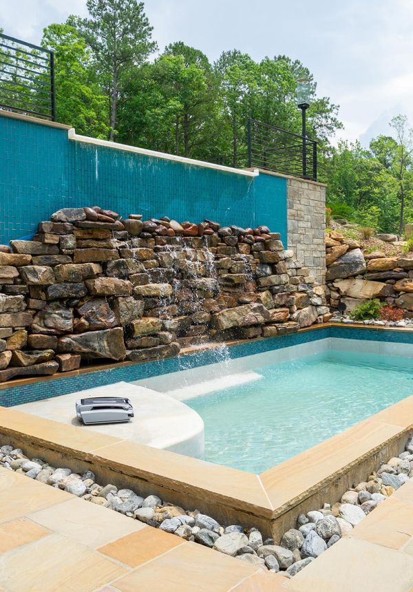 Outdoor swimming pool featuring a rock waterfall wall